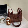 Détail d'un sac bandoulière en cuir marron avec fermeture éclair et breloque peluche - Grand / Avec Pendentif / Marron