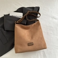 Brown faux suede hobo bag with adjustable strap and vintage brand label on white cloth - Brown