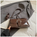 Primer plano de bolso retro marrón con hebilla de herradura plateada y textura de cuero - café
