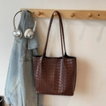 Detailed close-up of dark brown woven leather tote bag with cross-stitch craft on wood hook - Coffee
