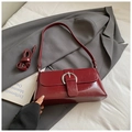 Detalle de bolso de hombro vintage rojo oscuro con hebilla plateada sobre blazer - Rojo