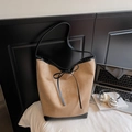 Brown suede bucket tote bag with black leather trim and bow detail on a bed - Khaki