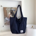 Detailansicht der dunkelblauen Canvas-Tasche mit Seitentasche und Markenlabel an der Wand - Marineblau
