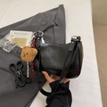 Chic black glossy underarm bag with teddy bear pendant on grey blazer background - Black with Pendant