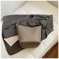 Close-up of taupe litchi grain leather bucket bag with silver hardware on a grey blazer - Gray