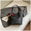 Black woven textured tote bag with colorful tassel charm on a grey blazer backdrop - Black with Pendant
