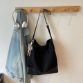 Retro black suede hobo shoulder bag with plush charm hanging on a wooden rack - With Charm / Black