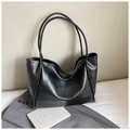 Detail of minimalist black tote bag with glossy leather texture and slim shoulder straps - Black