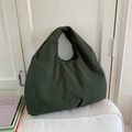 Dettaglio di una grande borsa hobo verde oliva in tessuto testurizzato su cuscino bianco - Verde
