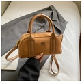 Detailaufnahme der braunen Wildleder-Boston-Tasche mit Ledergriffen auf grauem Blazer - Braun