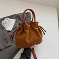 Detailansicht der braunen Wildleder Eimertasche mit Kordelzug und modischem Logo-Anhänger - Braun