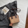 Retro kaki bucket bag met bruine handvatten en schouderband op een grijze blazer - Bruin Zonder Hanger