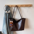 Detail view of large dark brown tote bag with glossy leather texture and bear charm - Coffee With Charms