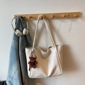 Close-up of off-white tote bag with pleated texture and a cute bear charm on a hook - Off-white With Pendant
