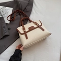 Detailansicht der beigen Ledertasche mit braunem Rand und goldenen Schnallen - Gebrochenes Weiß