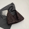 Detailansicht der Leopard-Tragetasche mit schwarzem Riemen auf grauem Anzug-Hintergrund - Schwarzer Leopard