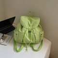 Detalle de mochila de nylon verde neón con cordón y bolsillos laterales en escritorio - Verde