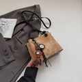 Close-up of brown suede bag with plush bunny charm and stylish black handles - With Pendant / Khaki
