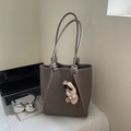 Close-up of litchi grain leather tote bag with knotted strap and cute bear charm - Gray With Pendant
