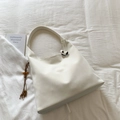 Detalle del bolso tote de lona crema con textura de cuero y adorno de borla de cuentas de madera - Blanco