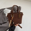 Detalle de un bolso cubo acolchado marrón con borla de cuentas y correa de hombro - Marrón
