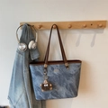 Sac cabas en jean bleu avec anses en cuir marron et pendentif peluche sur un vestiaire - Bleu avec Pendentif