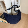 Dettaglio della borsa a mezzaluna in nylon blu navy con tracolla su pavimento chiaro - Blu scuro