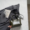 Olive green glossy crossbody bag with round handles and adjustable strap on a gray blazer - Green Without Pendant