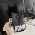 Elegante borsa a secchiello nera con coulisse, ciondolo a leone e tracolla larga - Nero con ciondolo