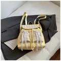 Detail eines hellgelben Rucksacks mit karierten Taschen und weißen Spitzenschleifen - Gelb