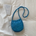 Close-up of a bright blue sequined crossbody bucket bag with a long shoulder strap - Blue