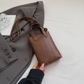 Donkerbruine geweven mini crossbody tas met knoopdetail op een grijs jasje - Koffie (Zonder Hanger)