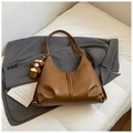 Detail view of caramel brown hobo bag with litchi texture and plush bear charm - Yellowish Brown With Pendant