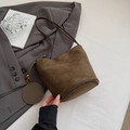 Braune Wildleder Beuteltasche mit rundem Münzfach auf dunkelgrauem Blazer Hintergrund - Grün