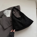 Detail of black suede tote bag featuring laser-cut floral patterns and sleek shoulder strap - Black