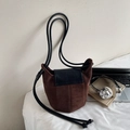 Minimalistische braune Wildleder-Umhängetasche mit schwarzem Leder auf Schreibtisch - Kaffeebraun