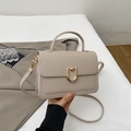 Close-up of golden U-shaped metal buckle and lychee pattern on off-white handbag - Khaki