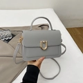 Detail shot of grey pebbled leather bag with gold horseshoe clasp and handle - Gray