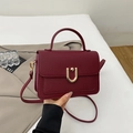 Detail view of burgundy lychee leather handbag with elegant gold U-shaped metal buckle - Burgundy