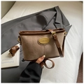 Detalle de bolso bandolera de ante marrón con costuras finas y placa de logotipo metálica - Caqui