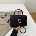 Close-up of black lychee grain leather handbag with elegant gold U-shaped metal lock - Black