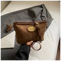 Detalle de bolso bandolera de ante marrón con placa metálica dorada y costuras finas - Marrón