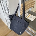 Dunkelblaue Jeans-Einkaufstasche mit weißen Kontrastnähten und Vordertaschen auf Stuhl - Blau