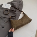 Sac hobo en daim marron avec anneaux dorés et bandoulière sur une veste de blazer grise - Vert