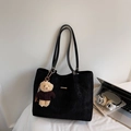 Detail einer schwarzen Stepp-Tote-Bag mit Goldleiste und einem niedlichen Teddy-Anhänger - Schwarz Mit Anhänger