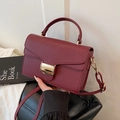 Detailed view of dark red litchi texture leather handbag with gold metal clasp closure - Burgundy