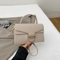Detail of beige litchi grain leather handbag featuring a large gold metal buckle - Khaki