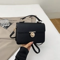 Detailed view of black litchi texture leather handbag with golden rotary lock buckle - Black