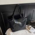 Detalle macro del bolso tote de cuero arrugado negro con elegante barra de logo dorada - Negro