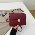 Detail view of burgundy pebble leather handbag with gold round lock and top handle - Burgundy